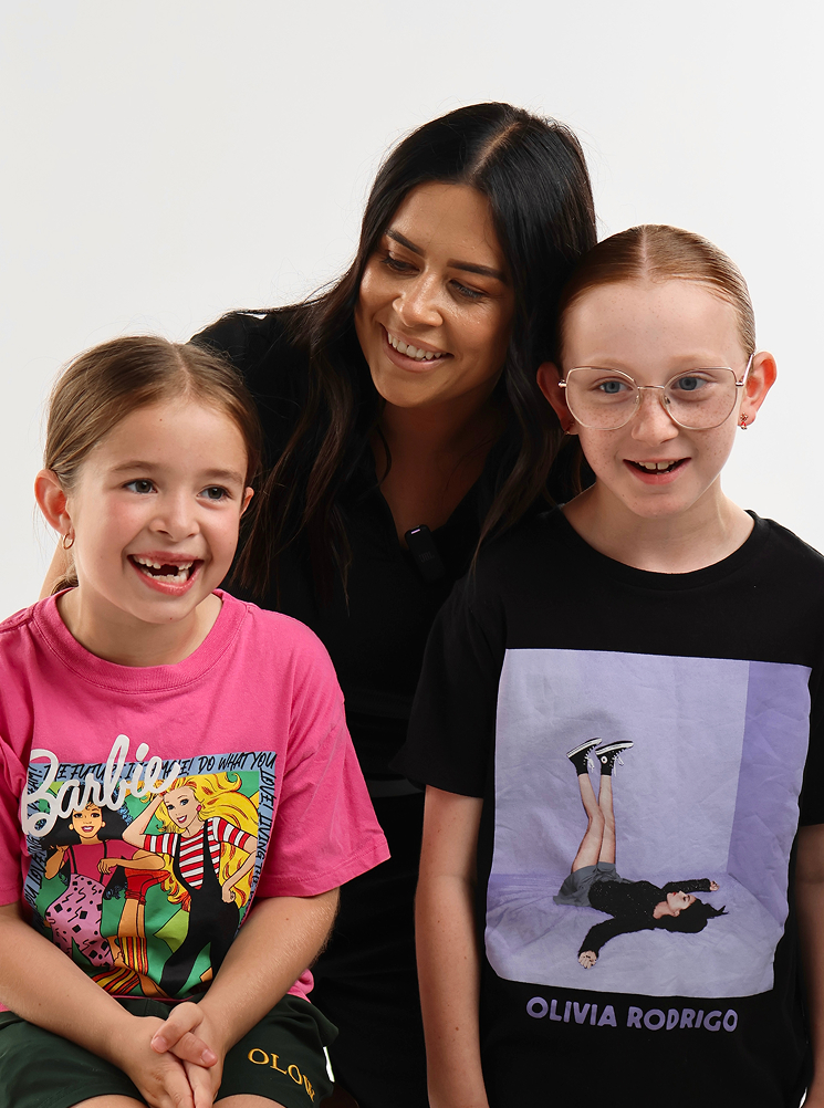 Two children smiling with their caring teacher
