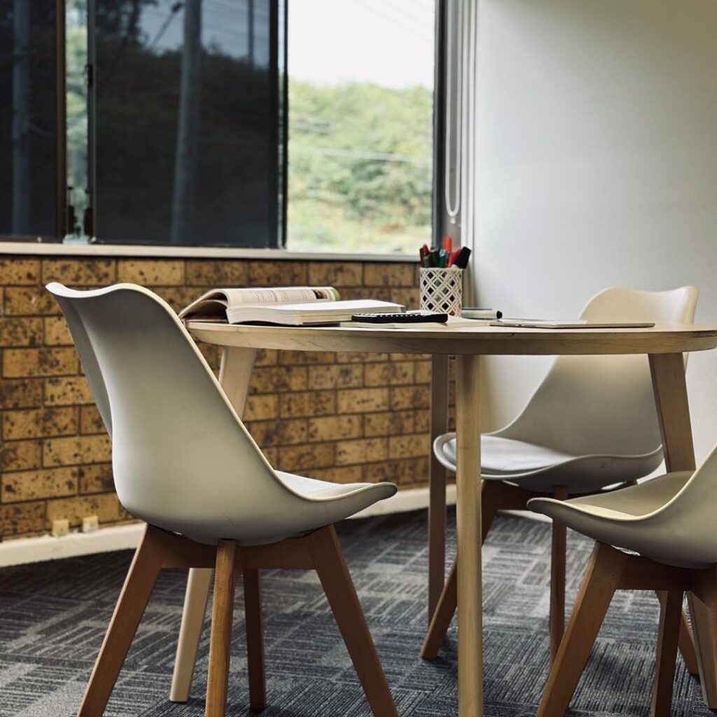 Book and pens placed on a table with chairs around it